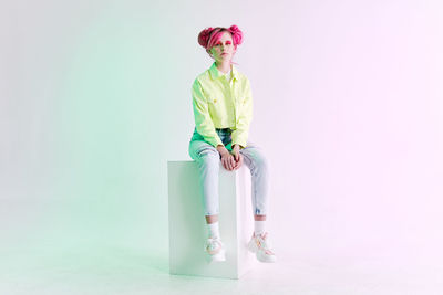 Portrait of young woman standing against white background