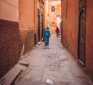 Rear view of people walking in alley