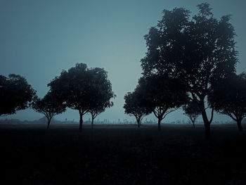 Silhouette trees on field against sky