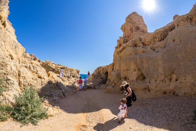 Mother and son holding hands while standing by rock formation