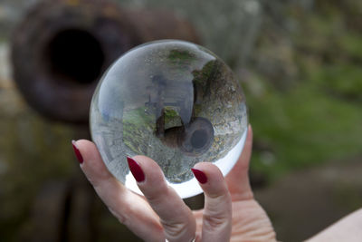 Woman holding crystal ball with reflection of cannon