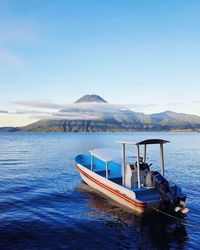 Boat moored on lake against sky