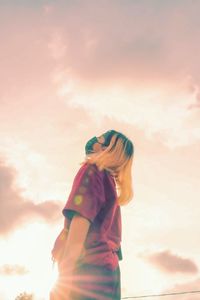 Low angle view of woman standing against sky during sunset