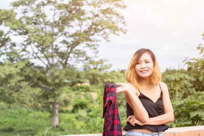 Portrait of smiling young woman sitting against plants