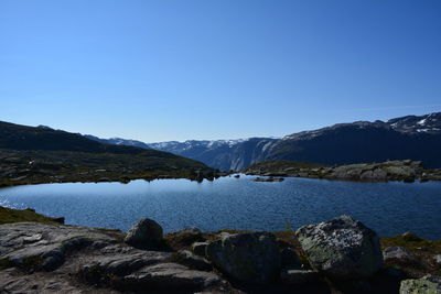 Scenic view of lake and mountains against clear blue sky