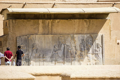 Rear view of people walking on old building