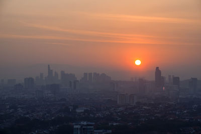 Modern buildings in city against sky during sunset