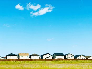 Houses on field against blue sky