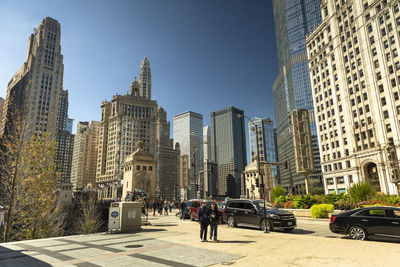 People on street amidst buildings in city against sky