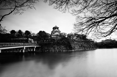 View of temple by lake against sky