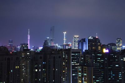 Illuminated buildings in city against sky at night