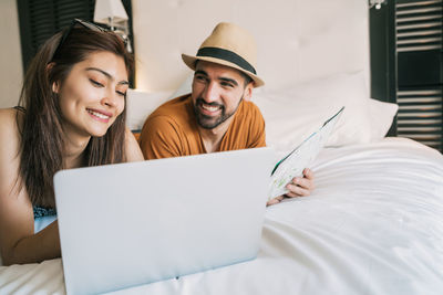 Portrait of smiling young woman using laptop on bed