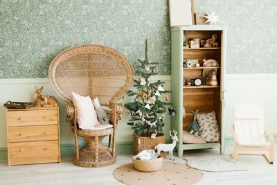 New year's decor of the children's room, wicker armchair with pillows, a christmas tree with toys,