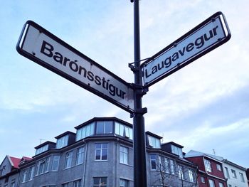 Low angle view of text on road sign against sky