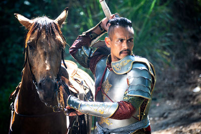 Man in warrior costume removing weapon by horse