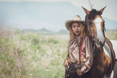 Woman with horse standing on land against sky