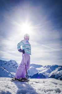 Woman skiing on snowy field during sunny day