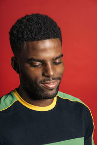 Portrait of smiling young man against red background