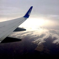 Aerial view of aircraft wing over landscape against sky