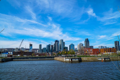 City skyline by river against sky