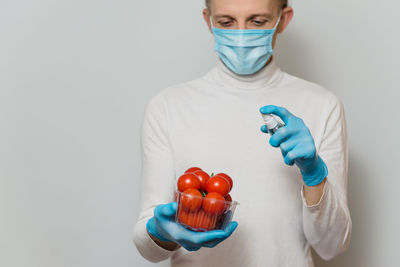 Midsection of doctor holding dentures against wall