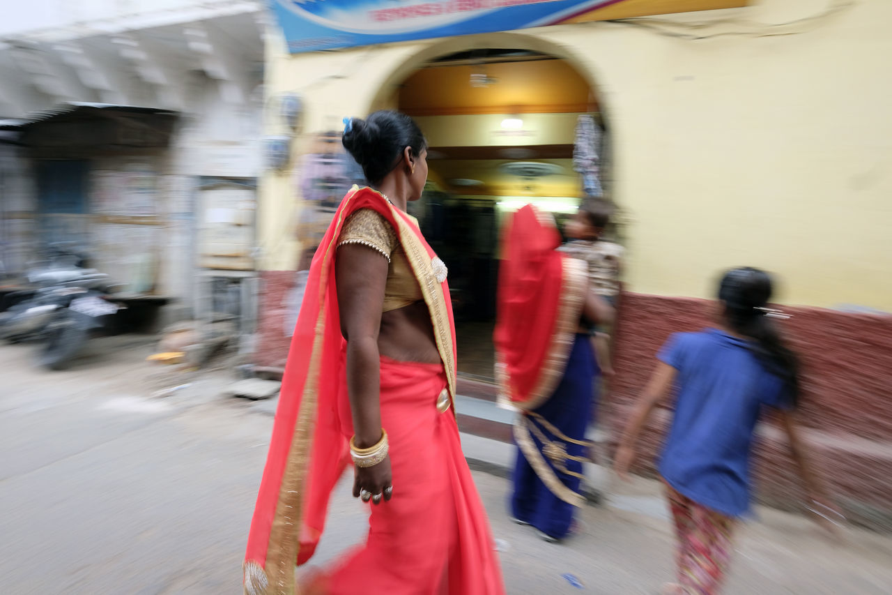 REAR VIEW OF PEOPLE WALKING ON ROAD