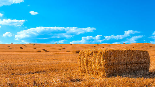 Hay bales on field against sky