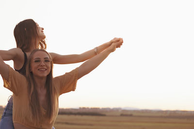 Two women holding hands at sunset in the field