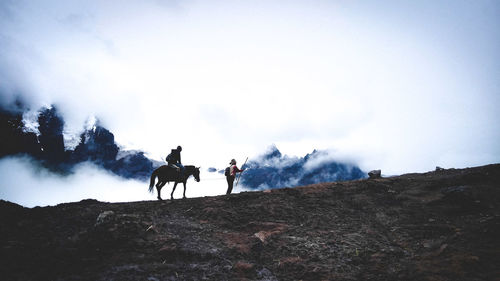 People riding horses on land against sky