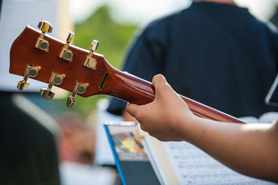 Cropped hand of woman playing guitar on stage