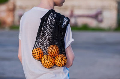 Rear view of boy holding fruits