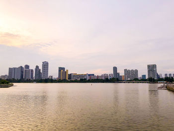 River and buildings against sky during sunset