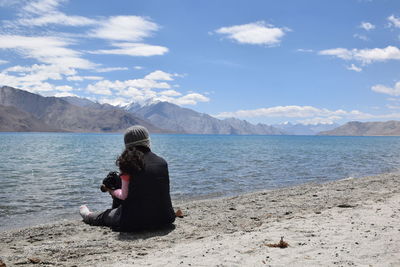 Woman sitting on beach against sky