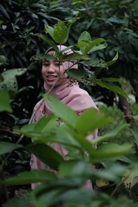 Portrait of smiling teenage girl standing amidst plants