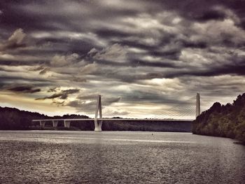 Bridge over river against cloudy sky