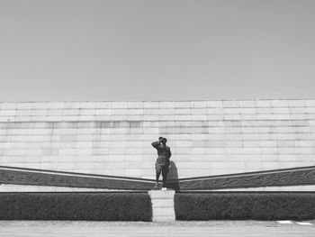 Man standing on wall against clear sky