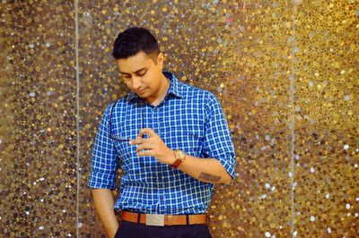 Young man standing against shiny wall