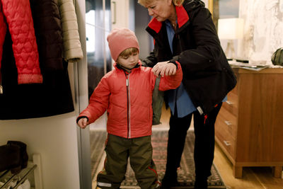 Senior woman helping grandson in wearing bag at home