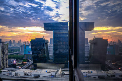 Modern buildings in city against sky during sunset