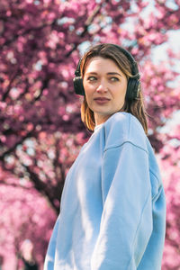 Portrait of young woman standing against trees