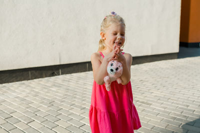 Portrait of cute girl standing against wall