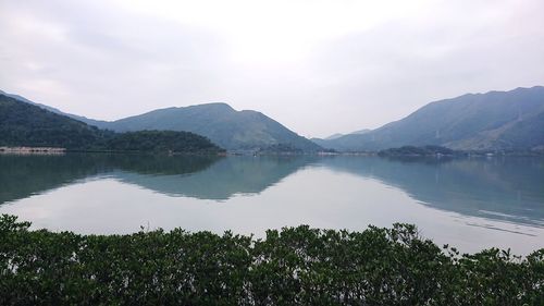 Scenic view of lake by mountains against sky