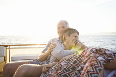 Rear view of couple sitting on shore against water