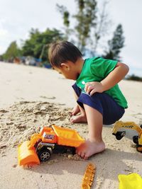 Boy playing with toy car on sand