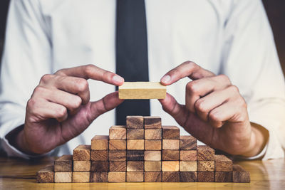 Midsection of businessman stacking wooden blocks on table