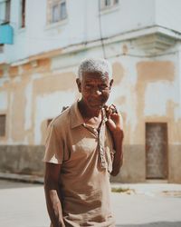 Man holding umbrella standing against building in city