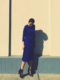 Full length of woman standing against wall