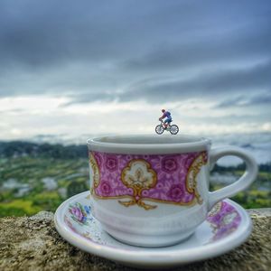 Close-up of figurine on cup against sky