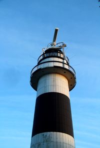 Low angle view of lighthouse by building against sky