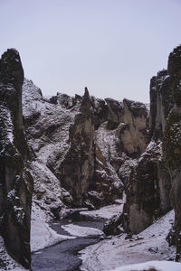 Rock formation on snow covered land against clear sky